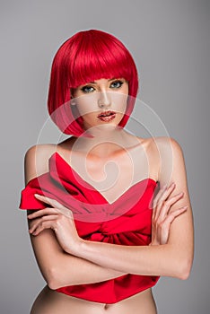 attractive woman with red hair and red top standing with crossed arms