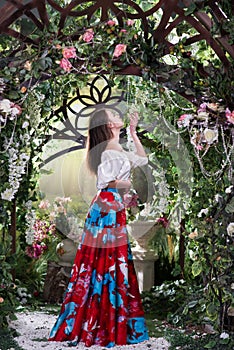 Attractive woman in red skirt in floral garden. Fairy tale