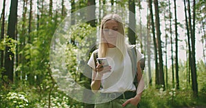 Attractive woman relax in forest and using smartphone outdoors. Woman Hiking In The Forest And Typing Message On