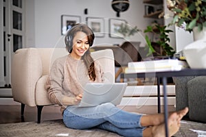 Attractive woman relaxing at home and using earphone and laptop