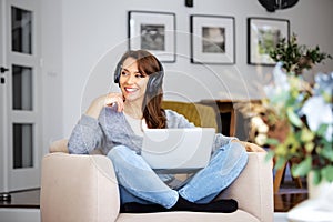 Attractive woman relaxing at home and using earphone and laptop