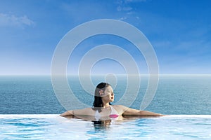 Attractive woman relaxing at infinity swimming pool