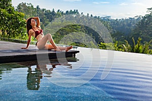 Attractive woman relaxing in luxury spa hotel at infinity pool