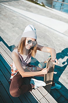 Attractive woman relaxing on the steps after longboard riding