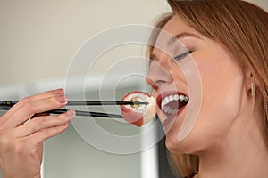 Attractive woman resting at home with sushi. Eating sushi with chopsticks close up, food takeout and delivery service