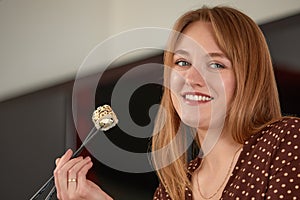 Attractive woman resting at home with sushi. Eating sushi with chopsticks close up, food takeout and delivery service