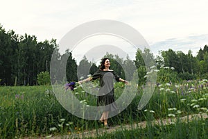 Attractive woman on the road in a summer field among Lupinus flowers.