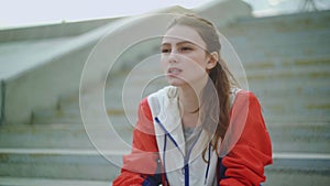 Attractive woman runner is sitting on stairs and resting exhausted after intense running workout training cardio