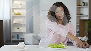 Attractive woman sadly choosing salad over cake, diet, weight control, nutrition