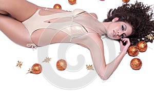 Attractive woman with shine gold bikini lying, Christmas balls around her