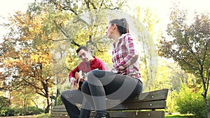 Attractive woman singing while man playing guitar in park