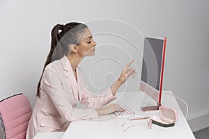 Attractive woman sitting at desk reading from computer screen.