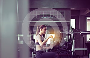 Attractive woman sitting and drinking water in gym,Asian female break and relex after workout