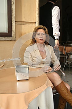 Attractive woman sitting in front of a trattoria in rome, lazio, italy