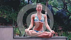 attractive woman sitting lotus yoga pose in spiritual relaxation serenity and meditation at stunning beautiful waterfall