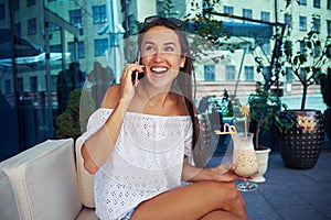 Attractive woman sitting on open terrace with cocktail in her ha
