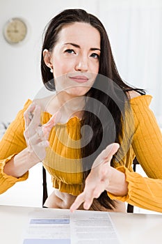 Attractive woman sitting by table and gesticulate