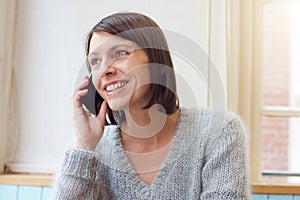 Attractive woman smiling with mobile phone at home