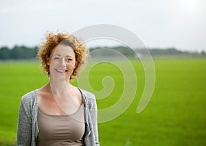 Attractive woman smiling outdoors by green countryside