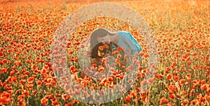 Attractive woman sniffing a poppy in field.