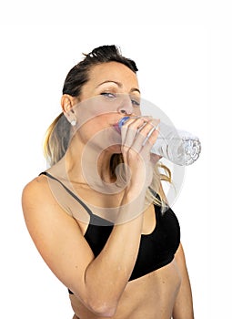 attractive woman in sport bra drinking water bottle at gym workout