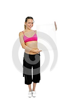 attractive woman in sport pants and gym bra holding blank billboard card with copy space