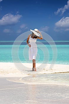 Attractive woman stands on a sandbank with turquoise waters and blue sky