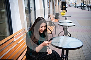 Attractive woman in a street cafe reading a text message from her phone