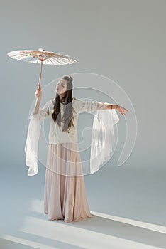 attractive woman in stylish winter outfit standing under japanese umbrella