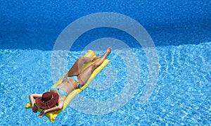 Attractive woman with sunhat relaxing on airbed