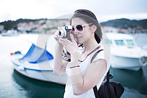 Attractive woman taking pictures with vintage retro camera laughing and smiling happy during summer holiday vacation travel