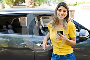 Attractive woman texting next to her car