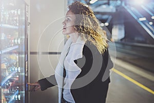 Attractive woman on transit platform using a modern beverage vending machine.Her hand is placed on the dial pad and she