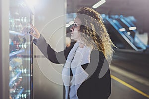 Attractive woman on transit platform using a modern beverage vending machine.Her hand is placed on the dial pad and she