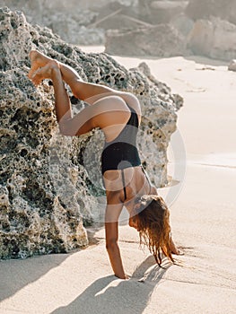 Attractive woman tries to stand on his hands, sexy girl in bikini at beach with sunshine