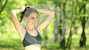 Attractive woman tying hair in ponytail getting ready for exercising. Beautiful young adult attaching her long hair on