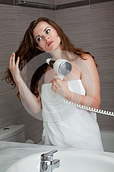 Attractive woman using fen in bathroom