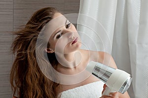 Attractive woman using fen in bathroom photo