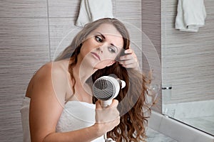 Attractive woman using fen in bathroom photo
