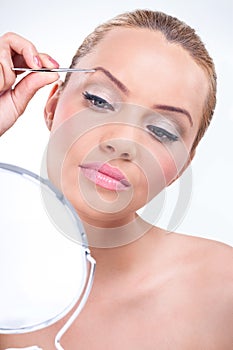 Attractive woman using tweezers