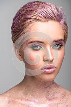 attractive woman with violet glitter on face and hair looking at camera
