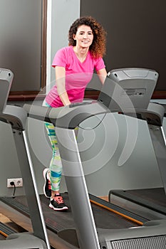 Attractive woman walking on running machine and smiling