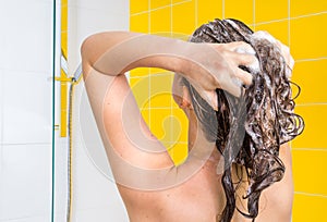 Attractive woman washing her hair with shampoo
