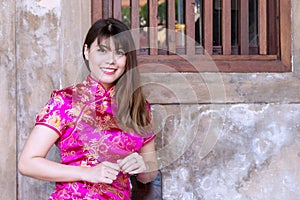 Attractive woman wear cheongsam deep pink dress looking at camera in Chinese New Year Festivities. Celebration concept