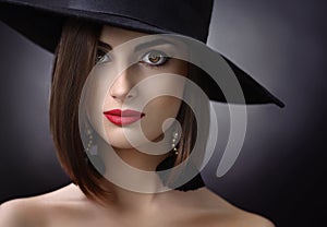 Attractive woman wearing a hat posing on black background