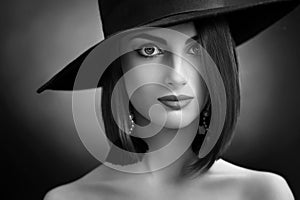 Attractive woman wearing a hat posing on black background