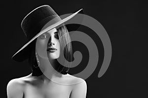 Attractive woman wearing a hat posing on black background