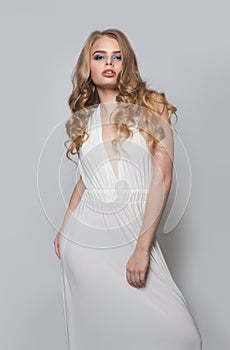 Attractive woman in white dress. Fashion model girl with blonde hair and makeup