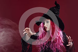 Attractive woman in witches hat and costume with red hair. Halloween