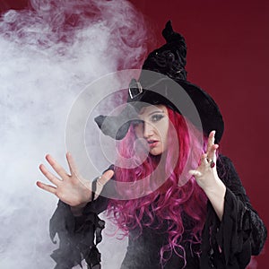 Attractive woman in witches hat and costume with red hair. Halloween